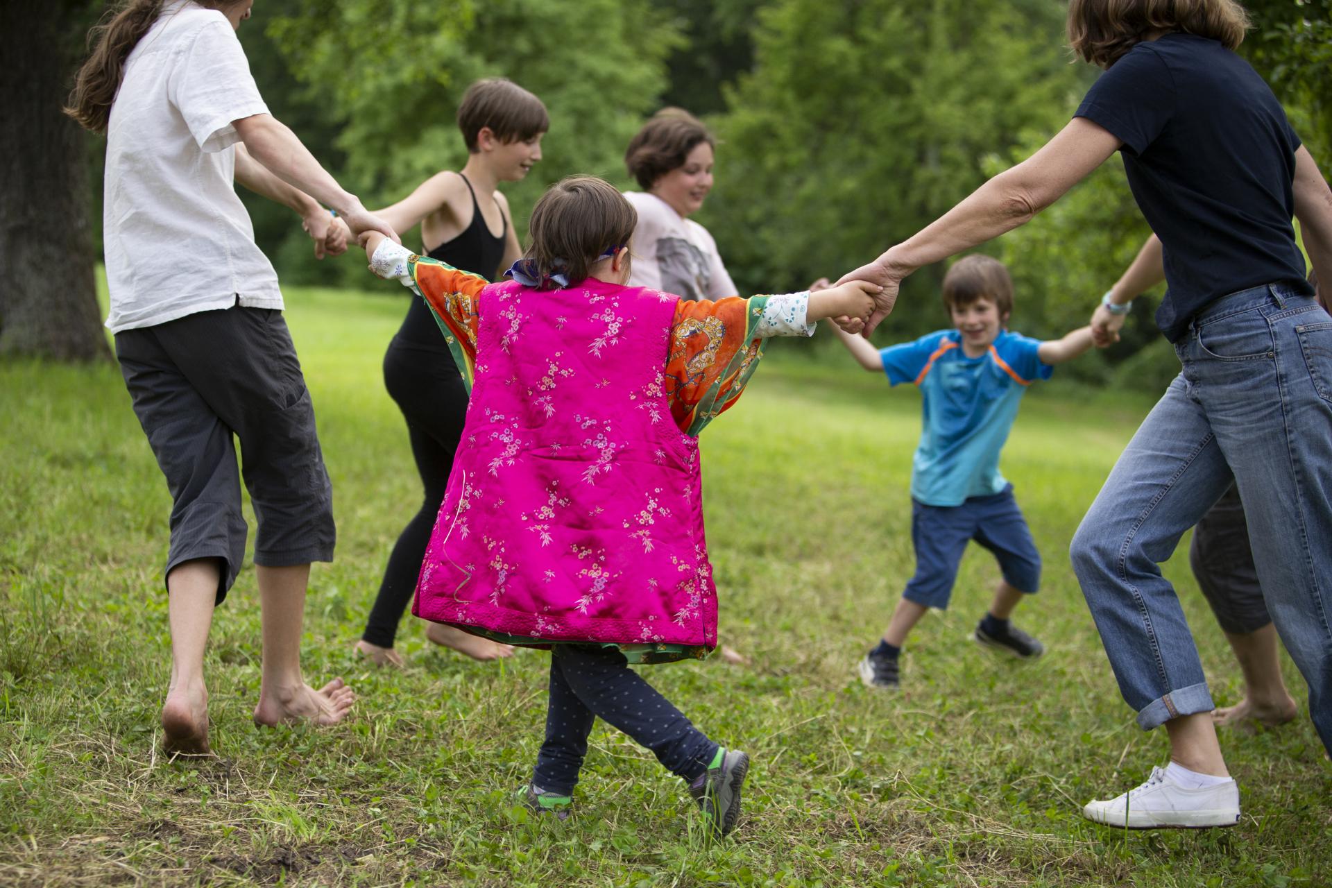 Kinder und Eltern, die auf einer Wiese im Kreis laufen